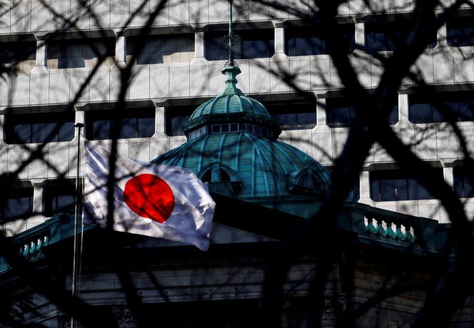 Le drapeau national japonais hissé au sommet du siège de la Banque du Japon est vu à travers les arbres à Tokyo, Japon, le 23 janvier 2025.