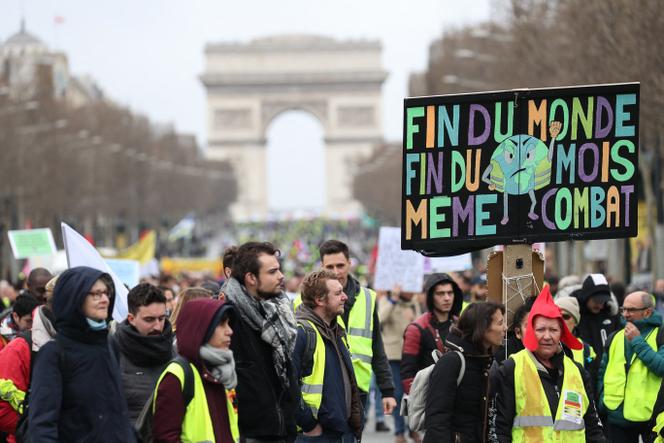 Des « gilets jaunes » brandissent une pancarte « Fin du monde, fin du mois : même combat », lors d’une manifestation, à Paris, le 9 mars 2019.