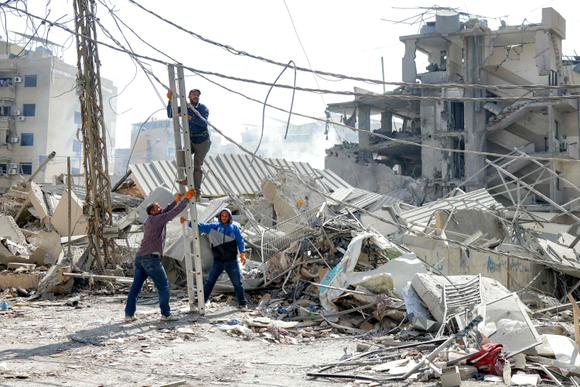 Los residentes intentan reparar un cable dañado por el derrumbe de un edificio tras un ataque aéreo en Hadeth, un suburbio del sur de Beirut, el 6 de junio de 2025.