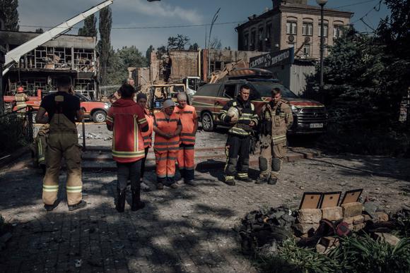 Kurtarma ekipleri, 6 Haziran 2025'te Kiev'de Rus bombardımanında hayatını kaybeden üç itfaiyecinin fotoğraflarının önünde saygılarını sunuyor.