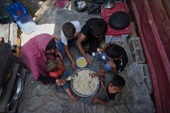 Tahrir Abu Jazar, de 36 años, comparte una comida de Eid al-Adha en un campamento de desplazados en Khan Yunis, una ciudad en el sur de la Franja de Gaza, el 6 de junio de 2025.