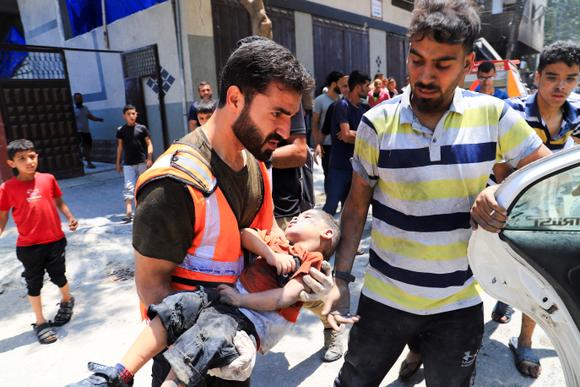Un homme porte le corps d’un enfant palestinien tué lors d’une frappe israélienne, à Gaza, samedi 7 juin 2025.