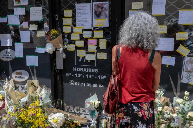 Une femme regarde les messages de condoléances et les fleurs affichés sur la porte du salon de coiffure où travaillait le coiffeur tunisien Hichem Miraoui, à Puget-sur-Argens (Var), le 8 juin 2025.
