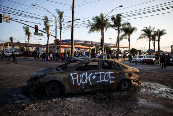 A destroyed car sits on the road during a standoff between police and protesters following multiple detentions by ICE in Paramount, California, on June 7, 2025.