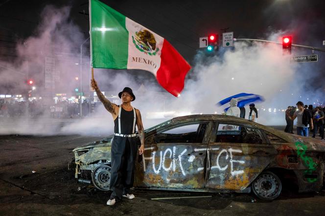 Na cidade de Compton, ao sul de Los Angeles, um homem brande uma bandeira mexicana durante manifestações de acordo com a intervenção da polícia de imigração (gelo).