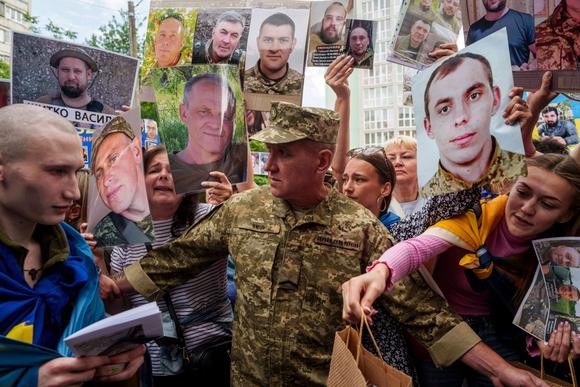 Ukraynalı bir asker, 9 Haziran 2025'te Ukrayna'nın Chernihiv Oblastı'nda kayıp kişilerin portreleri arasında esaretten dönüyor (solda).