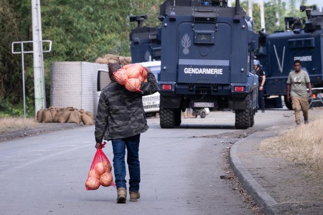 Un piéton transporte des légumes près d’un barrage de la gendarmerie française, à Saint-Louis, en Nouvelle-Calédonie, le 23 septembre 2024.