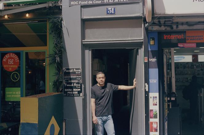 Alexandre Xu, 50 ans, pose, le 29 mai 2025, devant la porte de l’immeuble du 10ᵉ arrondissement où se trouvait le premier appartement qu’il a occupé, avec son frère et ses parents, à son arrivée à Paris, en 1987.