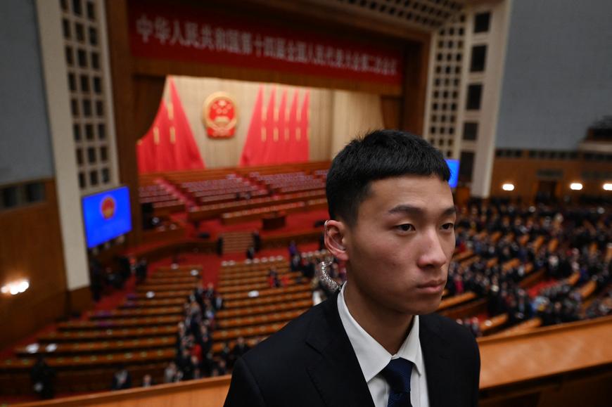 Un membre de la sécurité monte la garde alors que les délégués quittent le Palais de l'assemblée du peuple après la session d'ouverture de l'Assemblée nationale populaire à Pékin, en mars 2024.