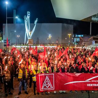 Porsche employees take part in a warning strike in front of the Porsche plant in Stuttgart-Zuffenhausen with torches and flags. IG Metall is calling on its members in the metal and electrical industry to take part in nationwide warning strikes from Tuesday.