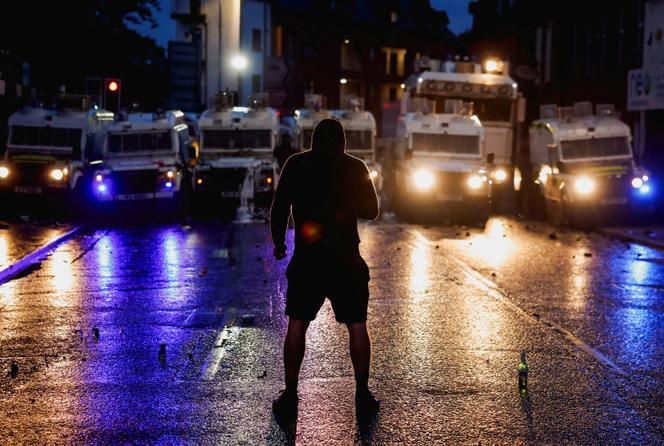 Un manifestant fait face à des véhicules de la police antiémeute à Ballymena, en Irlande du Nord, mercredi 11 juin 2025.