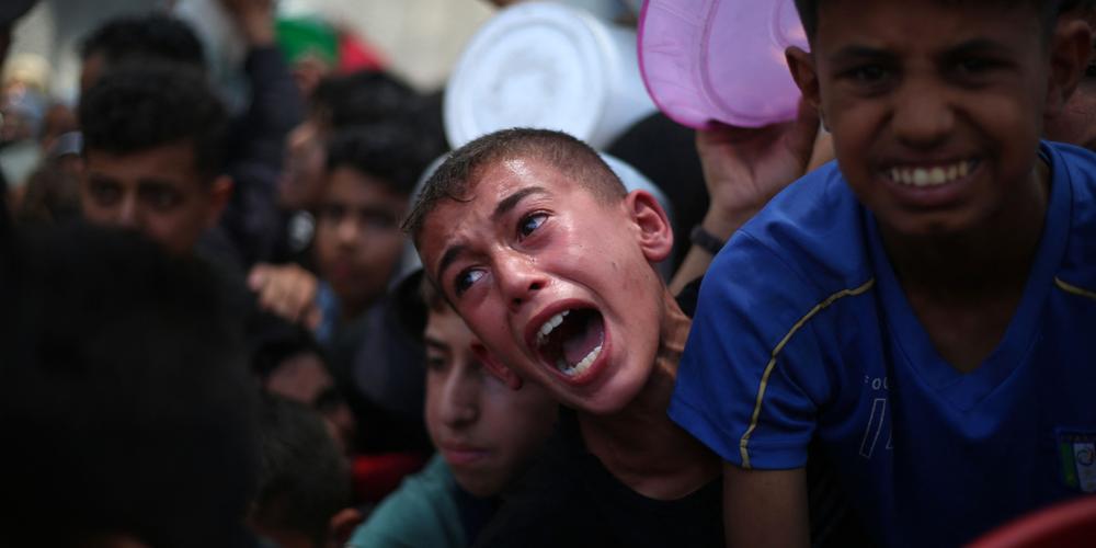 Des enfants palestiniens attendent de la nourriture à un point de distribution à Nuseirat, dans le centre de la bande de Gaza, le 11 juin 2025. - EYAD BABA / AFP