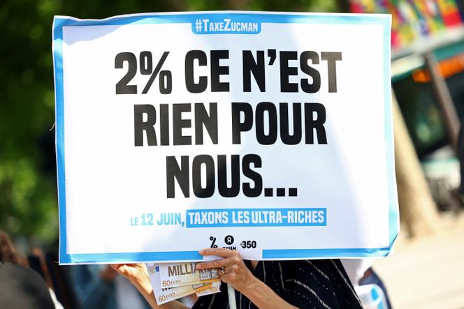 Pancarte lors d’une manifestation organisée par les ONG Attac, Oxfam France et 350.org à proximité du Sénat pendant l’examen du projet de loi Zuckman d’établir un impôt plancher de 2 % des ultrariches, le 12 juin 2025, à Paris.