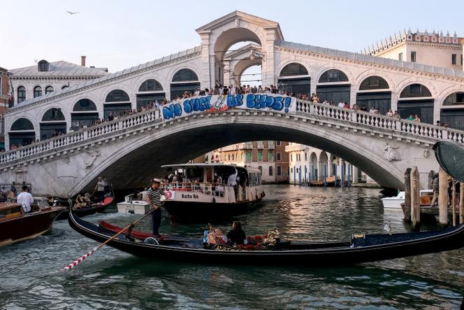 Des personnes manifestent contre l’organisation du mariage de Jeff Bezos avec Lauren Sanchez, sur le pont du Rialto, à Venise (Italie), le 13 juin 2025. Sur leur banderole est écrit « Pas de place pour Bezos ! ».