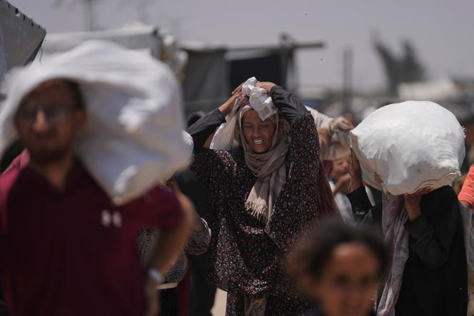 Des Palestiniens portent des sacs de nourriture distribués par la Gaza Humanitarian Foundation (GHF), à Rafah, dans le sud de la bande de Gaza, le 16 juin 2025.
