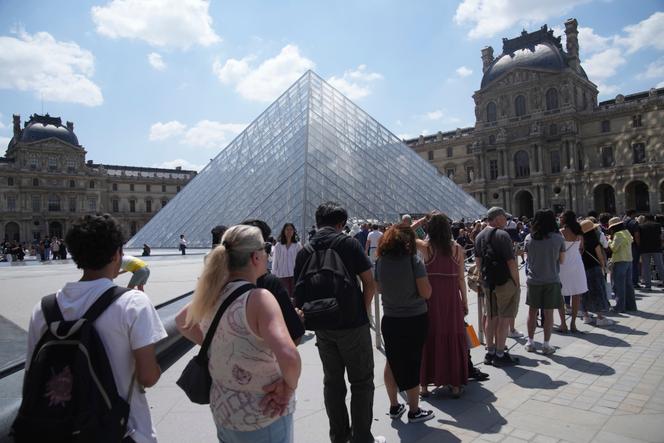 Des touristes devant le musée du Louvre, à Paris, le 16 juin 2025.