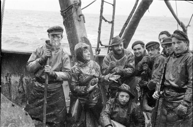 Anita Conti avec l’équipage du chalutier « Bois-Rosé-III » en pêche au large de Terre-Neuve, dans les eaux de l’Atlantique Nord, en 1952.