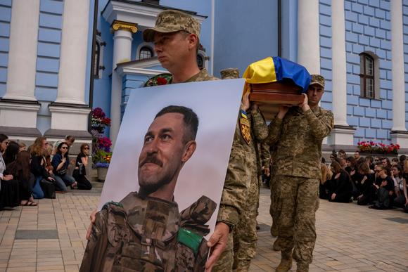 Des militaires ukrainiens portent le portrait et le cercueil de Iouri Felipenko, un acteur ukrainien mort au combat, lors de ses funérailles à Kiev, jeudi 19 juin 2025.