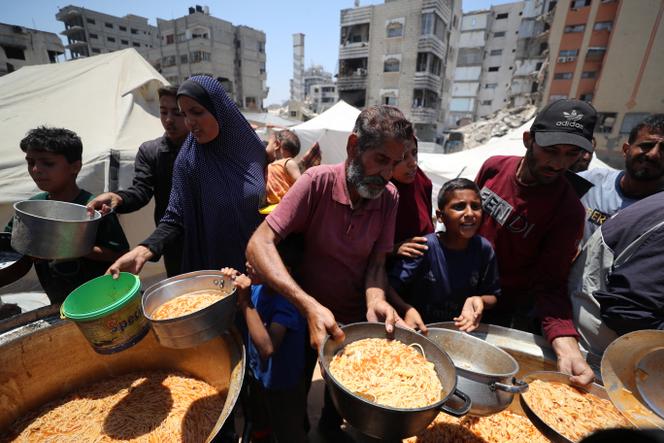 Des Palestiniens attendent de recevoir de la nourriture préparée par une cuisine caritative, à Gaza, le 21 juin 2025.