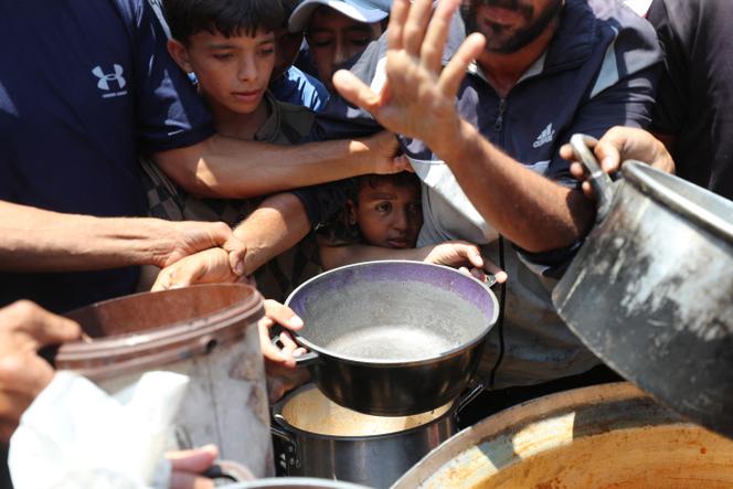 Des Palestiniens attendent de recevoir de la nourriture préparée par une cuisine caritative, à Gaza, le 21 juin 2025.