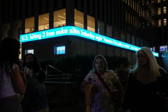 Des personnes passent devant un bandeau de Fox News affichant un titre sur les frappes américaines contre les installations nucléaires iraniennes, à New York, le 21 juin 2025.