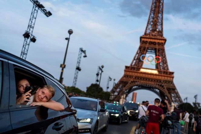  Passengers in the back of a taxi film themselves as they leave the Eiffel Tower, decorated with the Olympic rings ahead of the 2024 Summer Olympics, in Paris, on July 17, 2024.