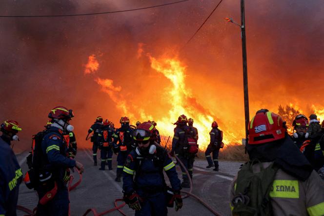 Des pompiers s’efforcent d’éteindre un incendie de forêt, attisé par des vents violents, qui a conduit à des messages d’évacuation près du village de Karyes, sur l’île de Chios, en Grèce, le 22 juin 2025. 