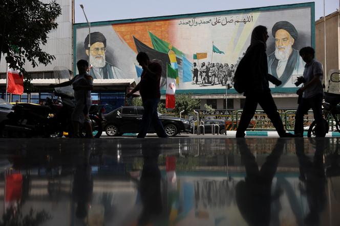 Des gens marchent à côté d’une fresque murale où est représenté le guide suprême de l’Iran, l’ayatollah Ali Khamenei, dans une rue, aux premières heures du cessez-le-feu avec Israël, à Téhéran, le 24 juin 2025.