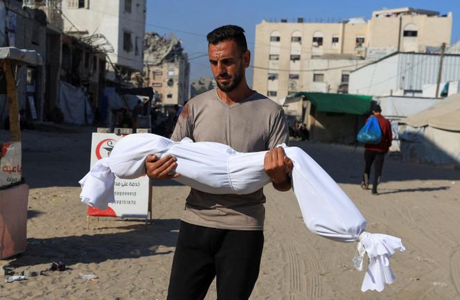 Un homme porte le corps d’un enfant, tué lors d’une frappe aérienne israélienne sur une maison, à Gaza, le 25 juin 2025.