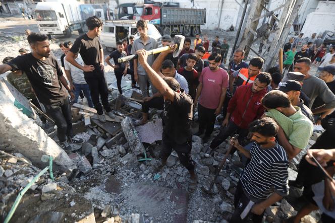 Des Gazaouis tentent de libérer le corps d’une personne bloquée sous les décombres à la suite d’une frappe israélienne nocturne, à Gaza, le 25 juin 2025.