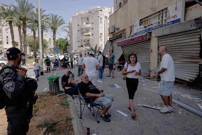Des habitants devant des commerces endommagés par des frappes iraniennes ayant fait cinq morts à Beersheba (Israël), le 24 juin 2025.