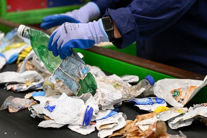 Contrôle manuel des divers emballages écrasés et transportés sur un tapis roulant dans le centre de déchets plastiques « surtri » à Epinal, le 28 juin 2024. 