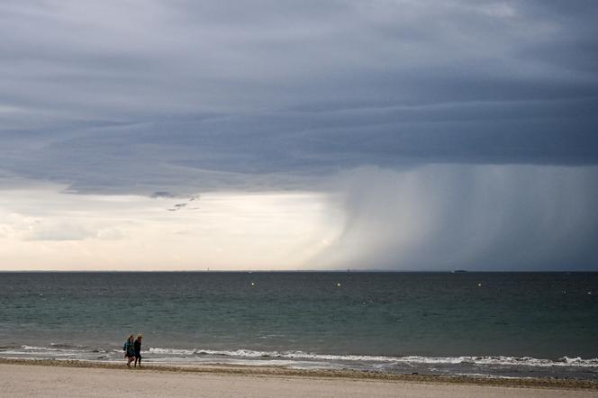 Des personnes marchent sur la plage sous de fortes pluies, lors d’un orage à La Baule (Loire-Atlantique), le 25 juin 2025. 
