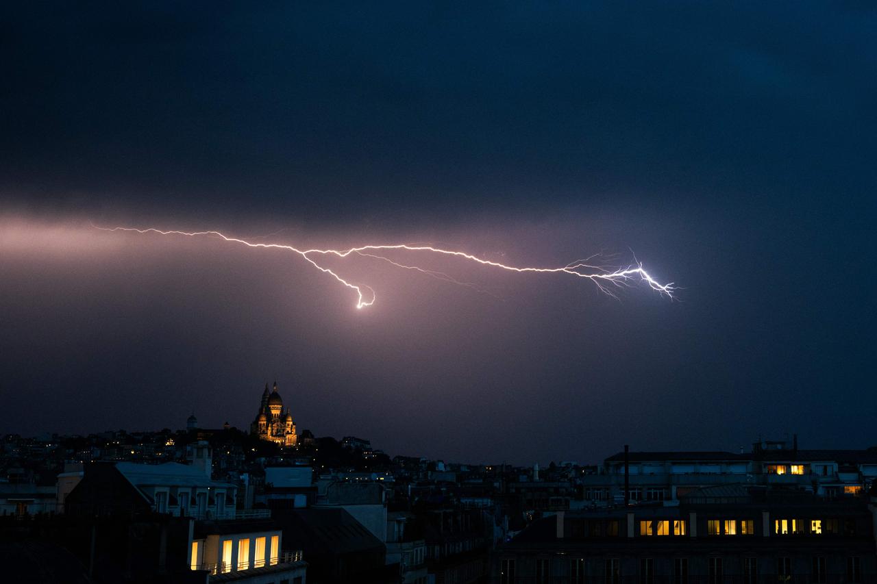 Un éclair illumine le ciel au-dessus de la basilique du Sacré-Cœur, à Paris, le 25 juin 2025.