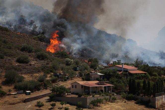 Des flammes s’élèvent près des maisons alors qu’un incendie de forêt fait rage, dans le village de Thymari, près d’Athènes, en Grèce, le 26 juin 2025.