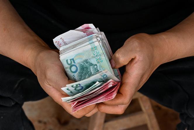 Un vendeur de légumes compte son argent dans une petite boutique du quartier de Putuo à Shanghaï, le 8 avril 2025.