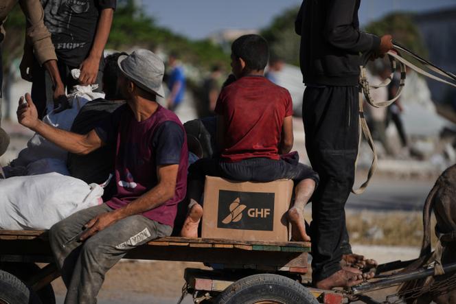 Des palestiniens transportent des cartons d’aide humanitaire distribués par la Gaza Humanitarian Foundation (GHF), à Khan Younès, le 26 juin 2025.