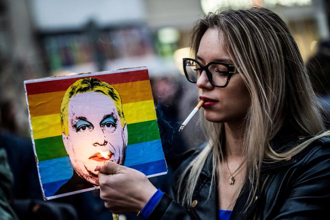 Une femme allume une cigarette devant un portrait du Premier ministre Viktor Orban, durant la Budapest, Pride, le 25 juin 2025. 