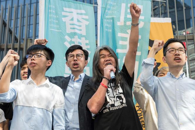 Le membre de la Ligue des sociaux-démocrates Leung Kwok-hung (au centre, en T-shirt noir et blanc), avec Joshua Wong, leader du mouvement étudiant prodémocratie (à gauche) et le parlementaire prodémocratie Nathan Law (à droite), à Hongkong, le 30 juin 2017.