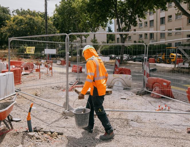 Des ouvriers des travaux publics construisent la ligne 5 de tramway à Montpellier, le 27 juin 2025. Compte tenu des très fortes chaleurs, leurs horaires de travail ont été aménagés, leur permettant de terminer leur journée de travail à 14 heures au lieu de 16 heures. Certains sont équipés de protège-nuque pour éviter les coups de soleil.