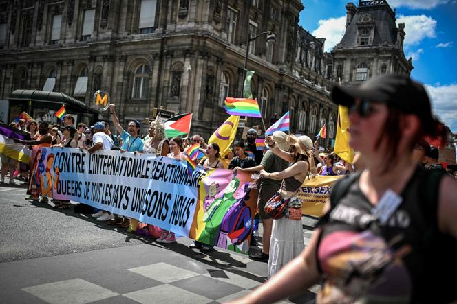 Des personnes se tiennent derrière une banderole sur laquelle on peut lire « Contre l’internationale réactionnaire. Queers de tous les pays unissons-nous » lors de la Pride à Paris, le 28 juin 2025.