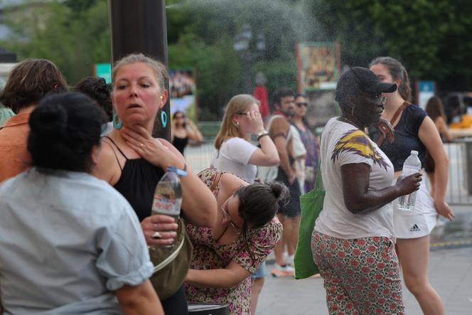 People cool off by walking through a fine mist of water in central Paris, June 21, 2025.