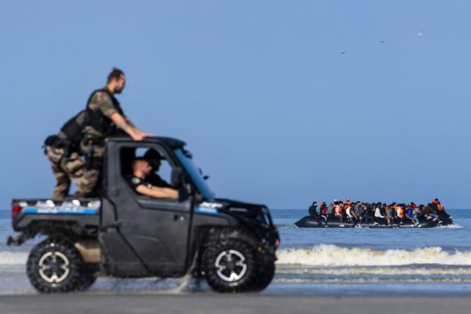 Os gendarmes franceses lideram um carrinho perto de migrantes que escalam um barco de contrabandista para tentar atravessar o canal da praia de Hardelot, em Neufchâtel-Hardelot (pas-de-calais), em 30 de junho de 2025.