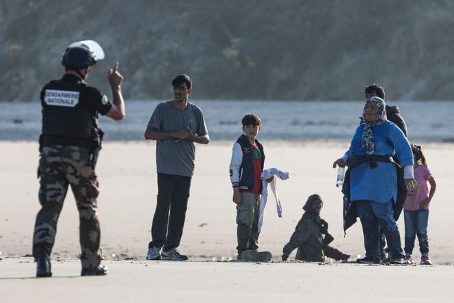 Un gendarme tente de dissuader un groupe d’exilés de faire la traversée avec un bateau de passeurs sur la plage d’Equihen (Nord-Pas-Calais), au bord de la Manche. Le 30 juin 2025. Sameer Al-DOUMY/AFP