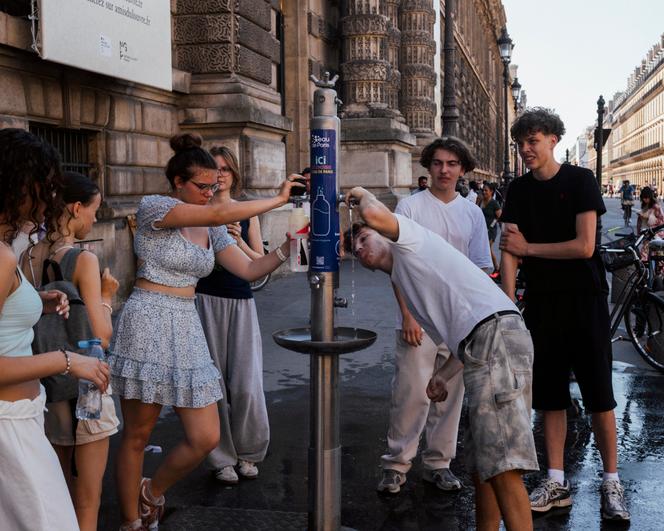 Tourists enjoy a installed water fountain near Place du Palais-Royal, in Paris, June 30, 2025. closed schools, nuclear reactor stop
