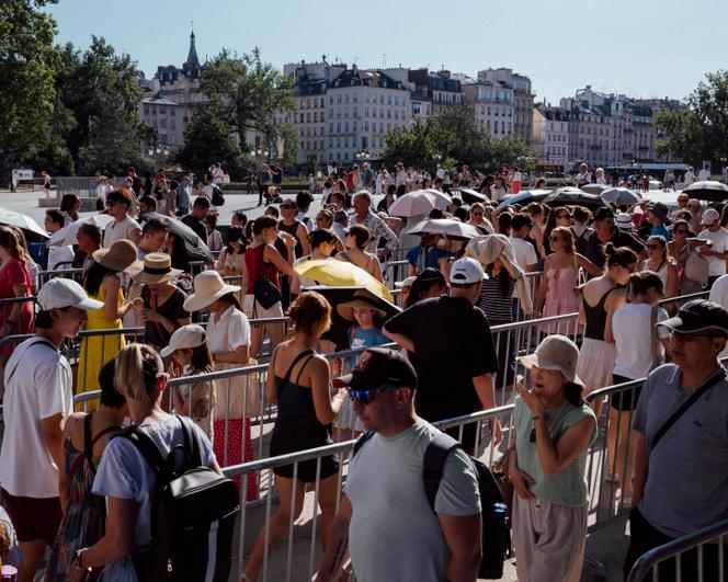 Des touristes tentent de braver le soleil dans la queue pour entrer dans Notre-Dame. A Paris, lundi 30 juin 2025.