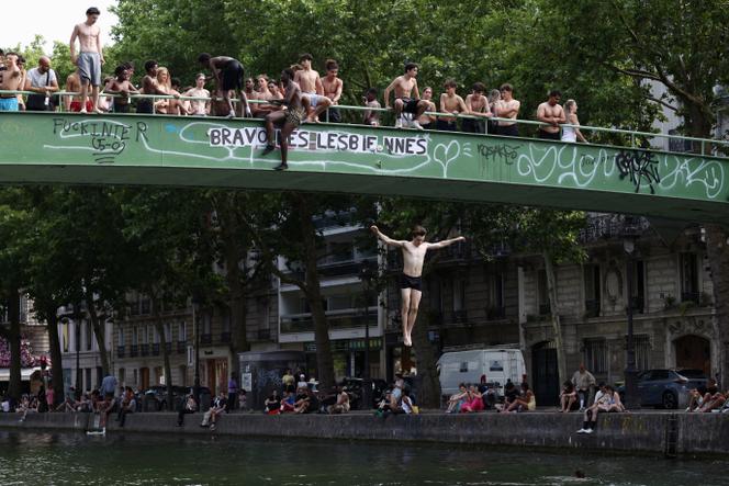 Des jeunes gens sautent d’un pont dans le canal Saint-Martin à Paris, le 2 juillet 2025.
