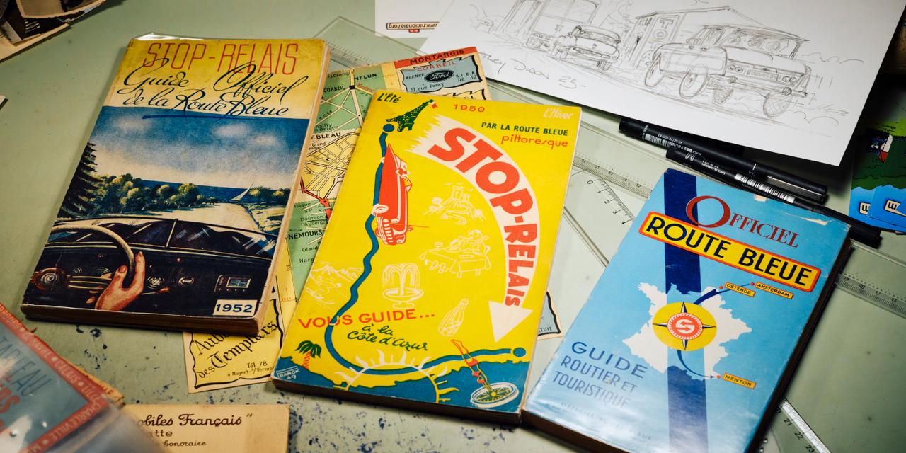 GUILLAUME BLOT POUR « LE MONDE » Sur la table à dessin de Thierry Dubois, des guides routiers des années 50 issus de sa collection, chez lui dans les Hauts-de-Seine, le 18 juin 2025.