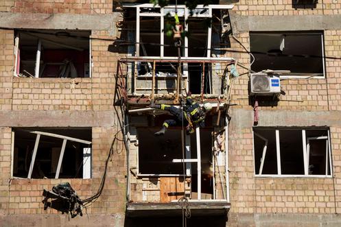Un pompier inspecte la façade d’un immeuble détruit par une attaque aérienne russe à Kiev, le 4 juillet 2025.
