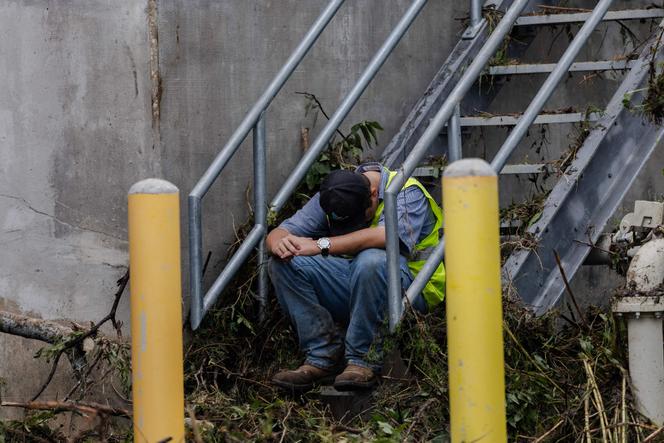 Um trabalhador de tripulação limpa faz uma pausa após a limpeza de detritos de árvores que foram alojados na lateral de um prédio ao lado do rio Guadalupe em 5 de julho de 2025, em Center Point, Texas.